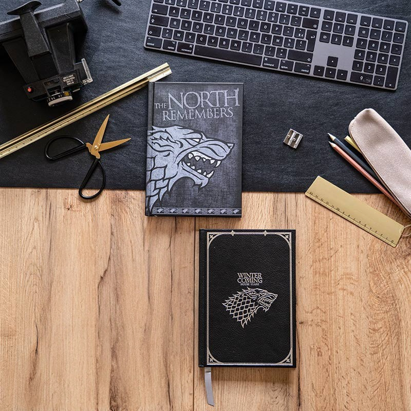 Fans Geek Store Game of Thrones House Stark A5 notebooks with direwolf sigil designs on a wooden desk