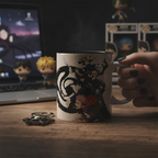 Fans Geek Store Jujutsu Kaisen ceramic mug featuring Tokyo and Kyoto sorcerers, held in a hand on a wooden desk.