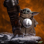 Fans Geek Store Iron Studios 1:4 scale polystone statue of Grogu standing beside The Mandalorian's armored boot.