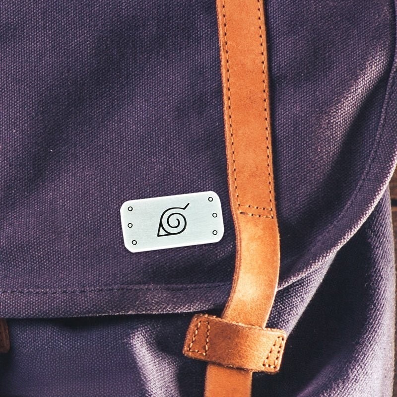 Fans Geek Store Naruto Shippuden Konoha symbol metal pin attached to a purple canvas backpack with leather strap