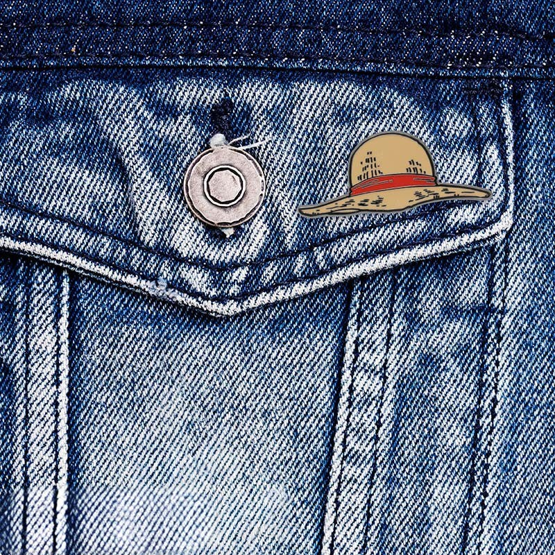 Fans Geek Store metal One Piece Luffy straw hat pin attached to a blue denim jacket pocket