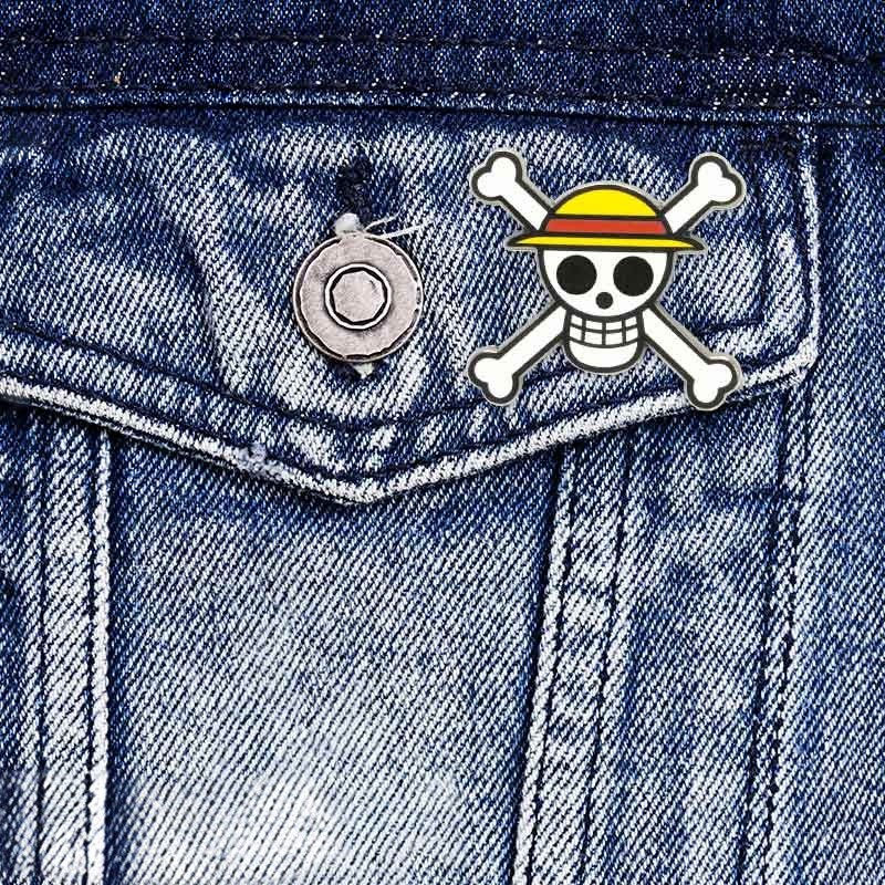 Fans Geek Store One Piece Straw Hat Skull metal pin attached to a blue denim jacket pocket