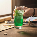 Fans Geek Store One Piece glass featuring Zoro Jolly Roger filled with a green drink held by a hand