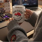 Fans Geek Store ceramic Pokémon Trainer mug with Poké Ball design held by a person at a gaming desk