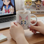Fans Geek Store Sailor Moon ceramic mug featuring Luna and Artemis, held by hands on a desk with a laptop and figures.