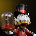 Fans Geek Store Uncle Scrooge McDuck statue holding a dollar sign under glass. Features red coat, black top hat, and glasses.