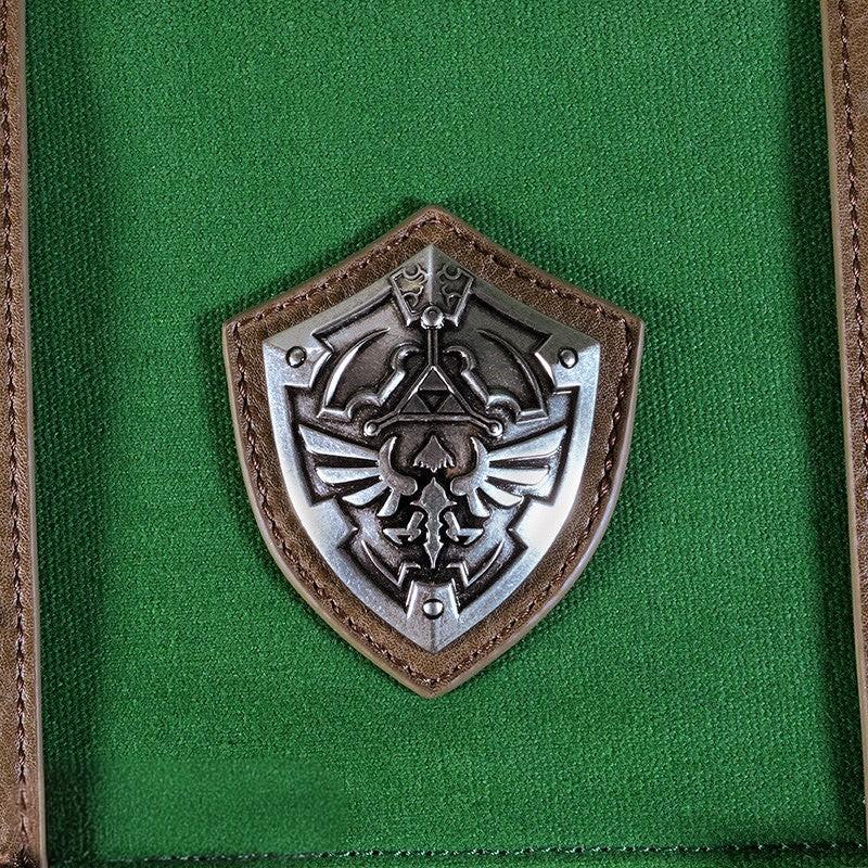 Fans Geek Store The Legend of Zelda backpack featuring a detailed silver Hylian shield emblem on green fabric